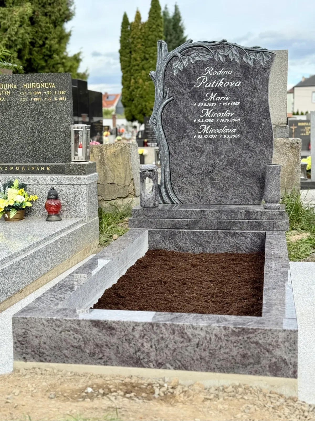 Žulový pomník s plastickým motivem stromu, rytým písmem, vázou a lucernou